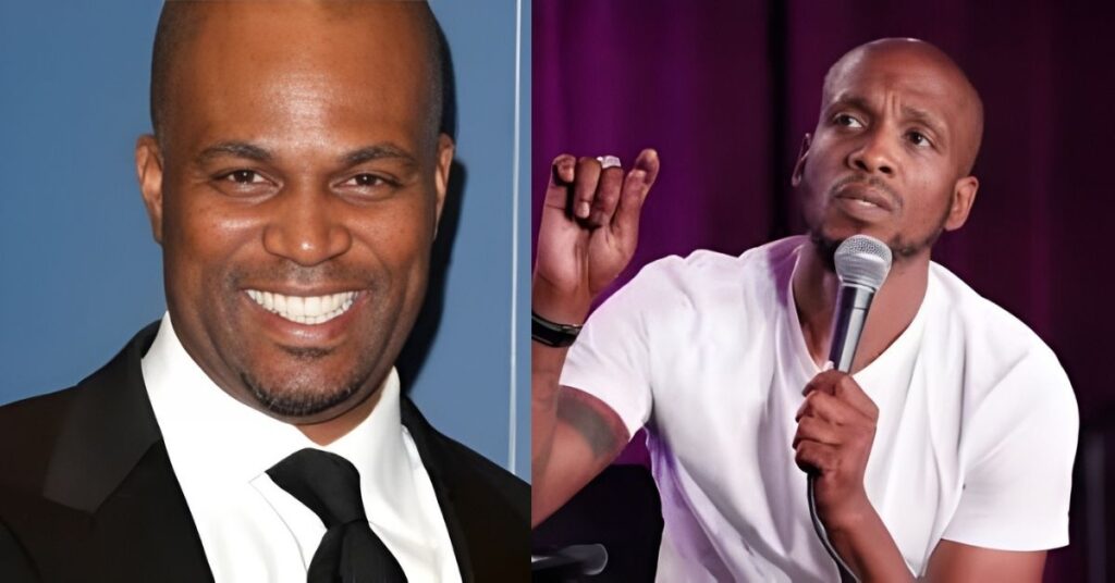 A man in a white t-shirt holds a microphone and speaks into it while gesturing with his left hand.