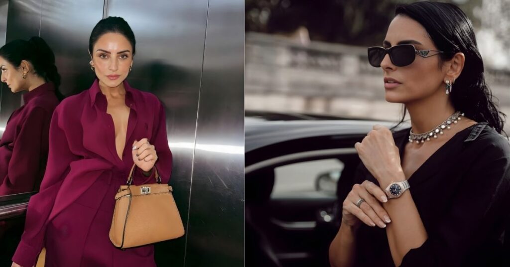 A person in a deep purple dress and holding a brown handbag stands in front of a mirrored wall.