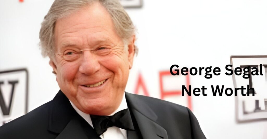 A smiling person is wearing a suit and bow tie.