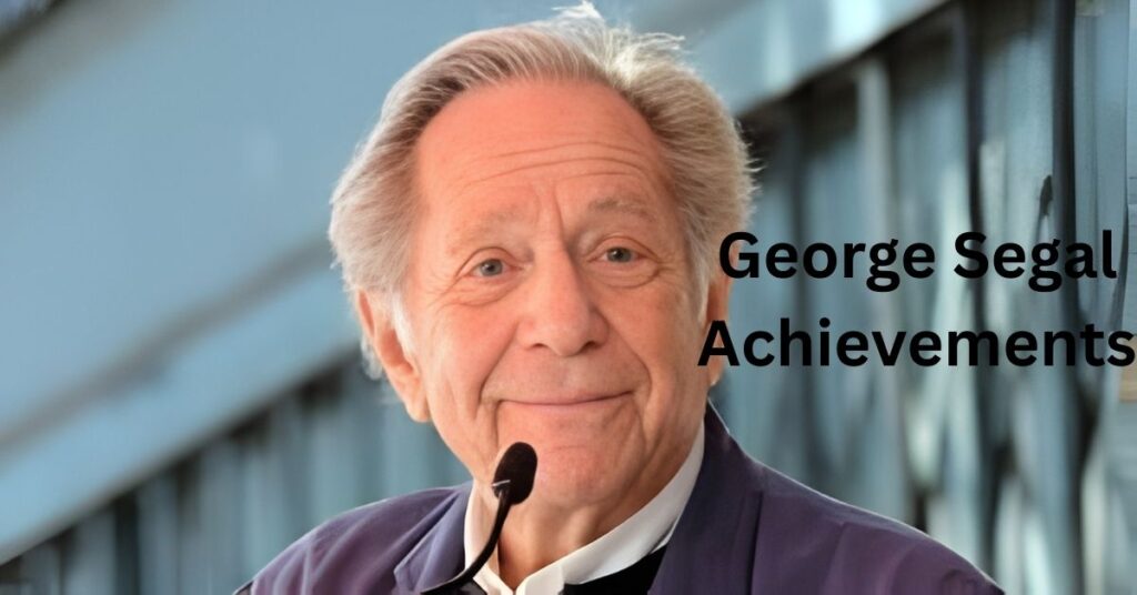 George Segal stands in front of a microphone.