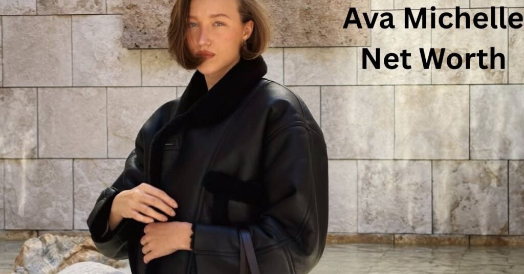 Ava Michelle, wearing a black leather jacket with a fur collar, stands in front of a stone wall with a water feature.