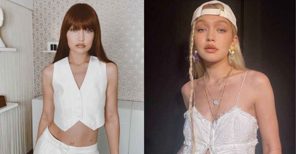 Gigi Hadid, wearing a white baseball cap, a white ruffled top, and multiple layered necklaces. They have a braid with a charm and large earrings.