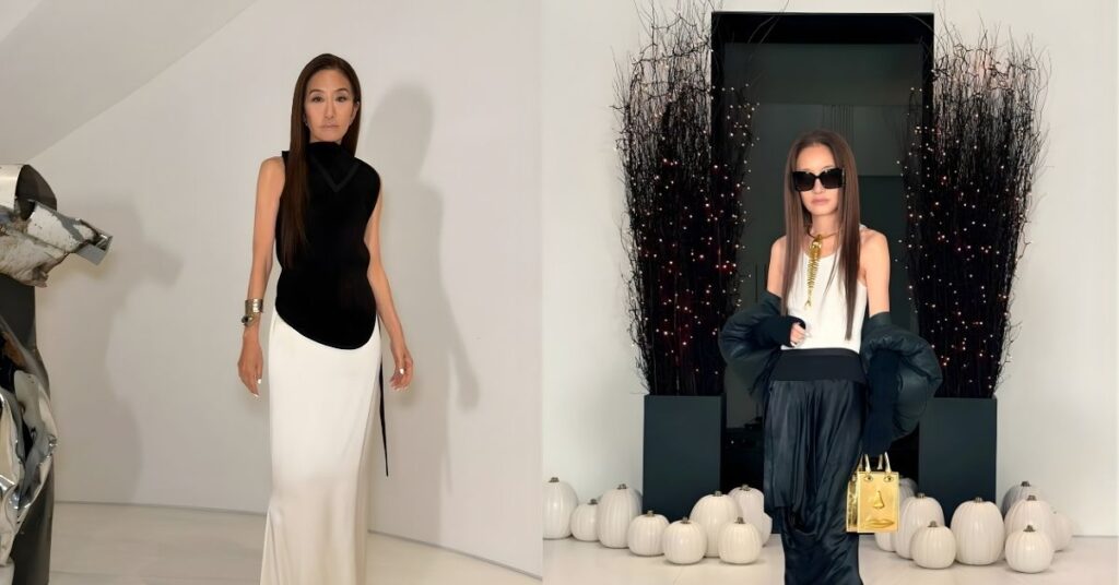 Vera Wang stands in a white room wearing a black sleeveless top and a long, flowing white skirt. A silver bracelet is on their left wrist.