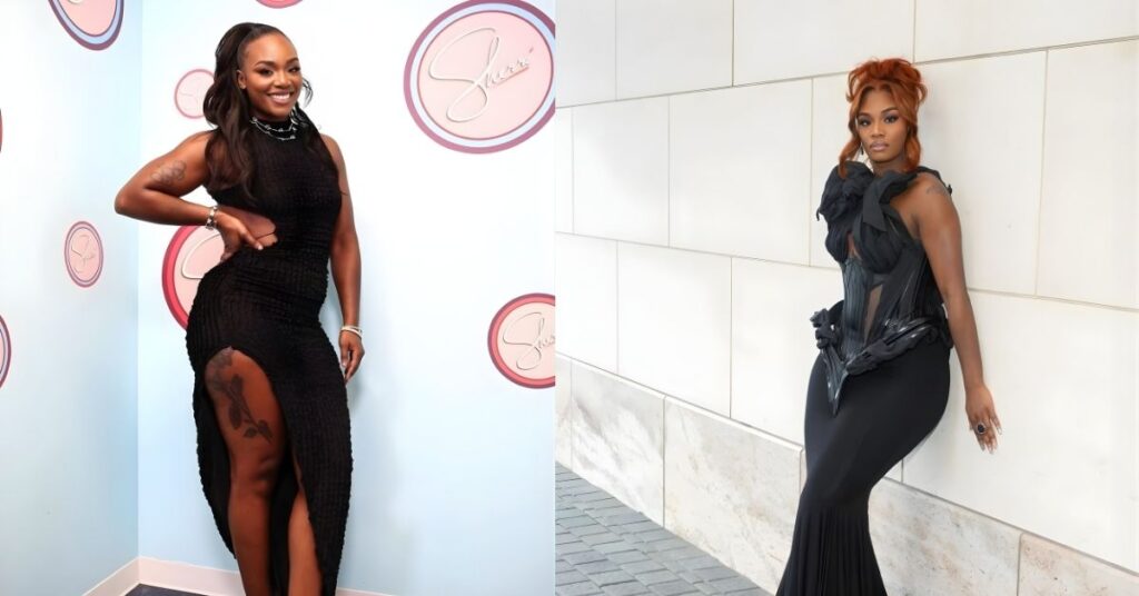 Claressa Shields, wearing a black ruched dress with a high slit and platform heels, stands in front of a light blue wall with circular logos.
