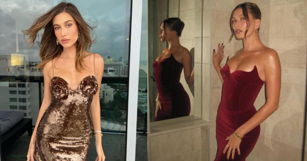 Hailey Bieber, in a strapless deep red velvet gown, stands next to a mirror, with their reflection visible on the left.