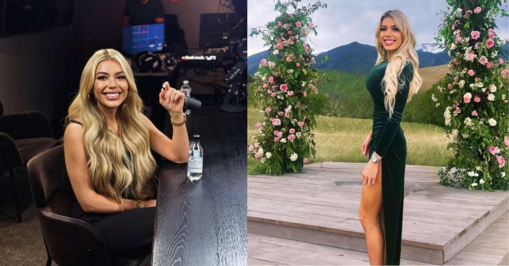 Hannah Hammond, in a dark green velvet dress with a high slit, stands on a wooden stage, framed by floral arches, with a mountainous landscape in the background.