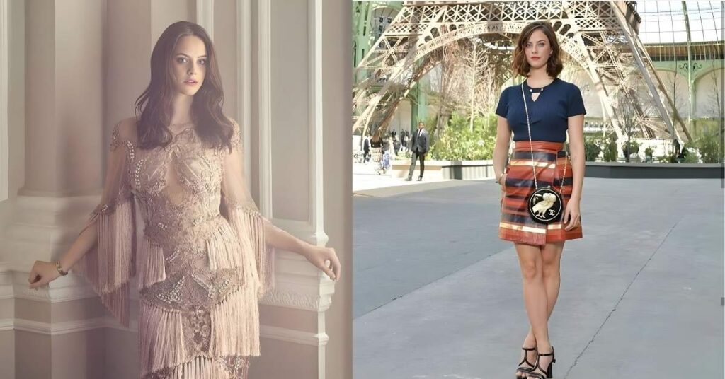 Kaya Scodelario models a detailed, ornate, fringed dress with a plunging neckline and long, sheer sleeves adorned with intricate beading and embellishments.