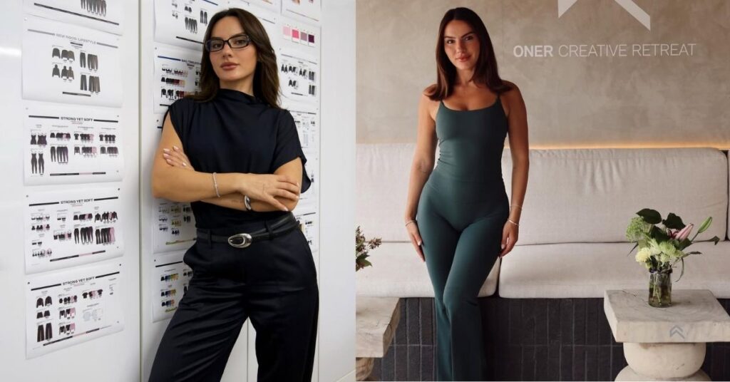 Krissy Cela, wearing a dark green jumpsuit, stands in front of a wall with the words ONE CREATIVE RETREAT and a logo.