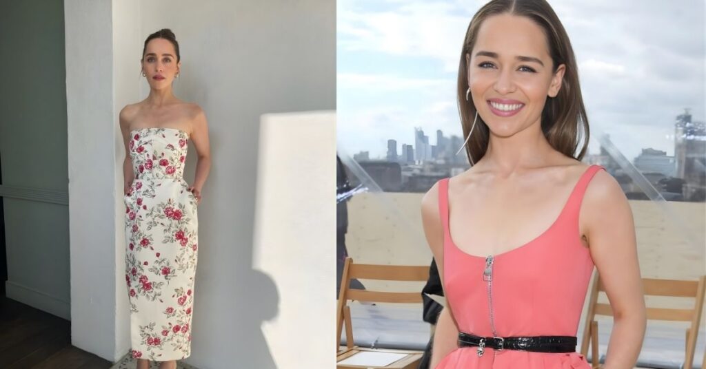 Emilia Clarke smiles while wearing a sleeveless coral dress with a silver zipper and a black belt, with a city skyline in the background.
