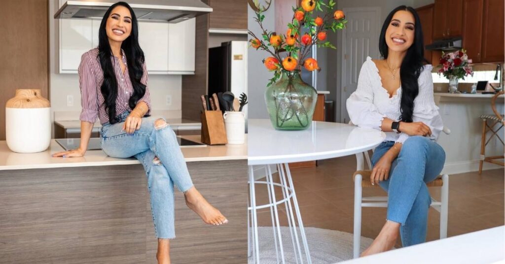 Stephanie Buttermore, with long dark hair wearing a striped shirt and ripped jeans, is sitting on a kitchen counter with legs crossed.