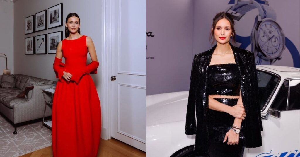 Nina Dobrev, in a bright red, floor-length gown with flared sleeves, stands in a room with a sofa and framed artwork on the wall.
