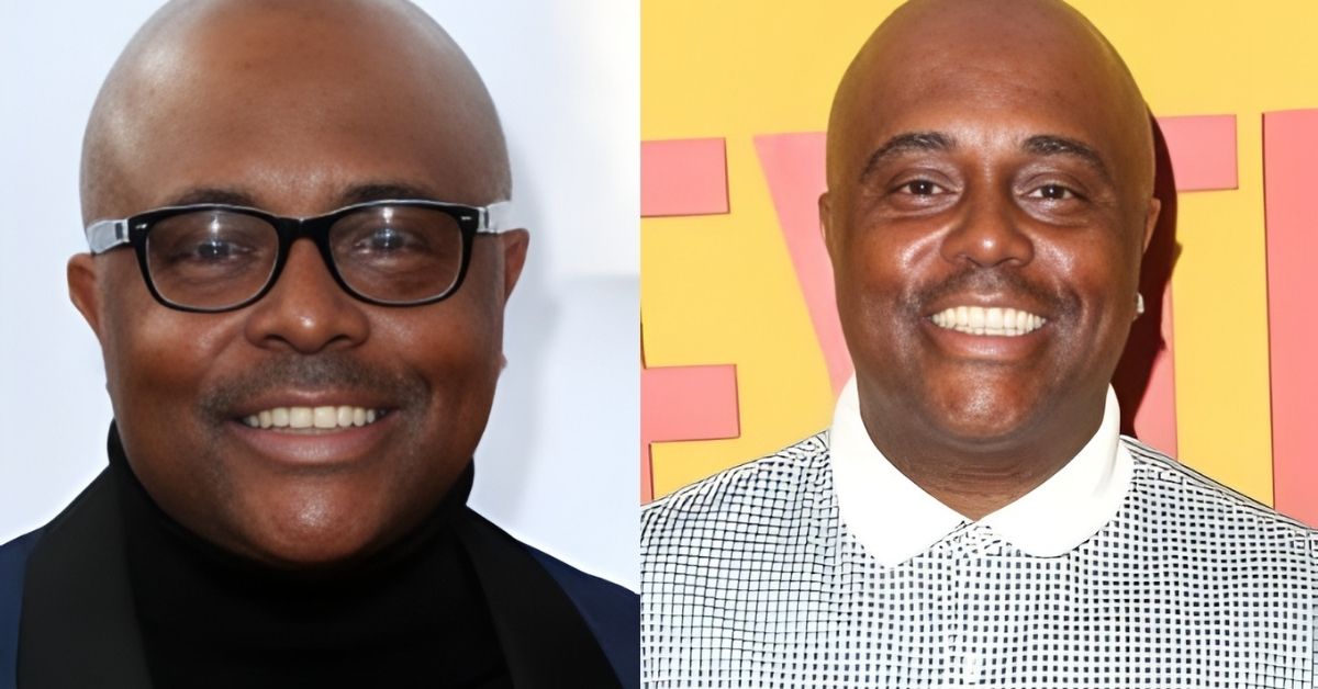 A man with glasses and a black turtleneck smiles at the camera.