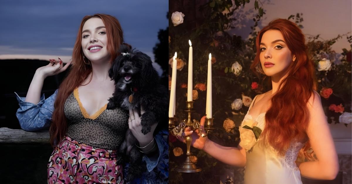 Caylee Hammack, with long red hair wearing a light-colored slip dress, stands near a candelabra with lit candles and a backdrop of roses.