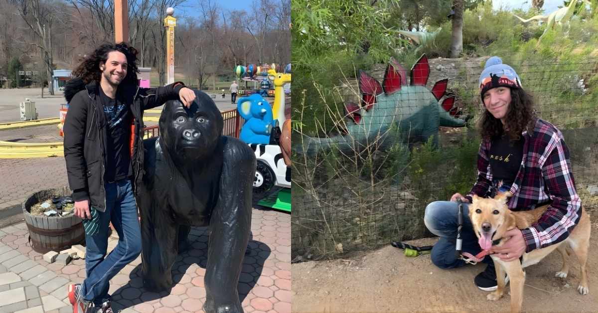 Dan Avidan kneels with a dog in front of a dinosaur statue.