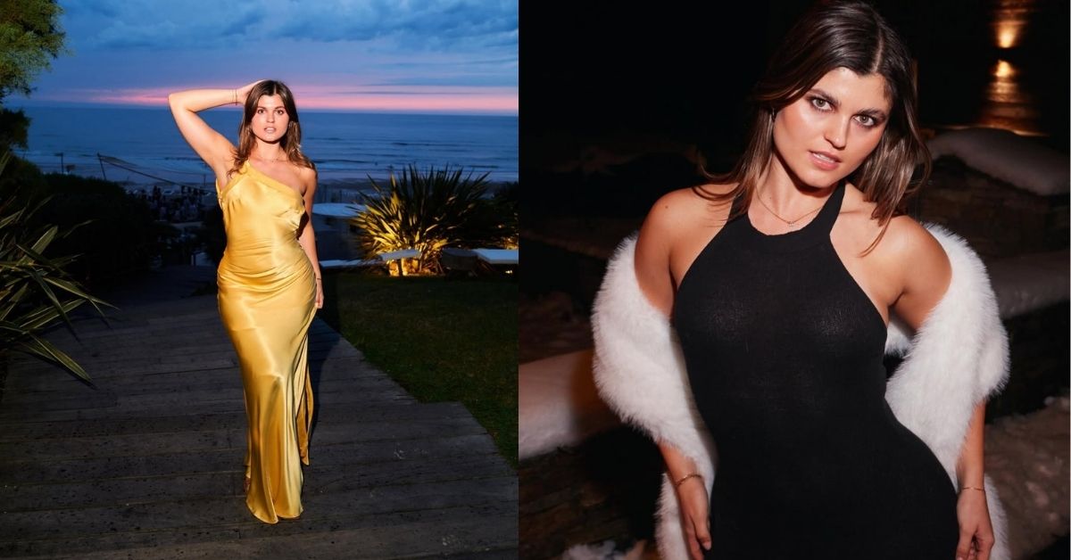 Elle Edwards, wearing a black halterneck dress and a white fur stole, is posing in a dimly lit outdoor setting with snow visible.