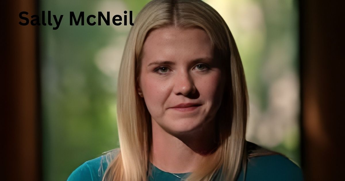 Sally McNeil shot with blonde hair, wearing a teal shirt, against a blurred green background.