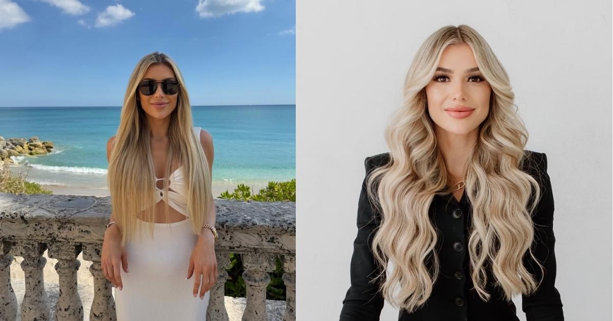 Hannah Hammond, wearing a white dress and sunglasses, stands on a balcony overlooking the ocean with a beach and rocks to the left.